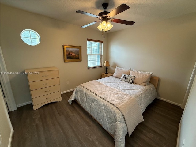 bedroom with ceiling fan, dark wood-type flooring, and a textured ceiling