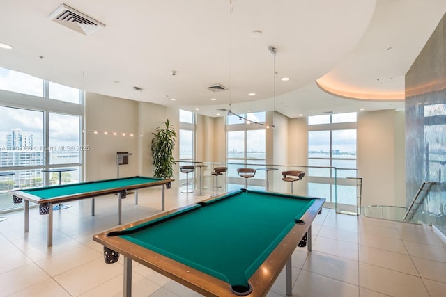 playroom featuring a water view, a tray ceiling, billiards, and a wall of windows