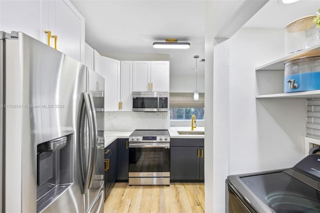 kitchen featuring pendant lighting, sink, light hardwood / wood-style floors, white cabinetry, and stainless steel appliances