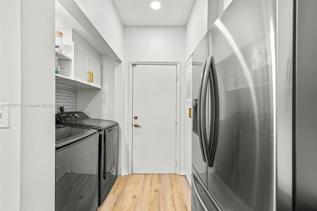 clothes washing area with light hardwood / wood-style floors and washer and clothes dryer