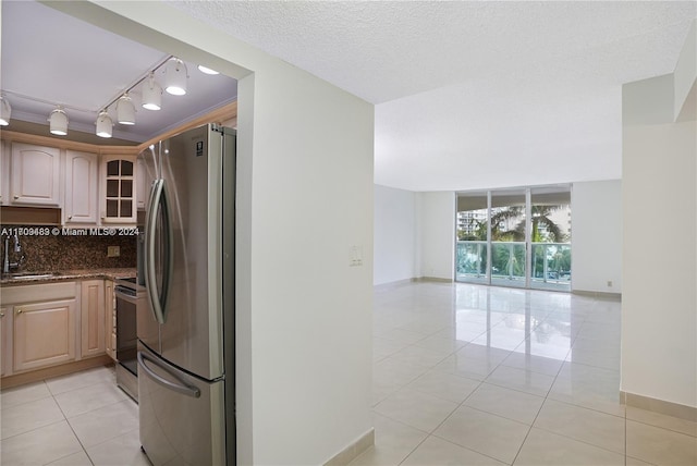 kitchen with track lighting, tasteful backsplash, a textured ceiling, stainless steel appliances, and sink