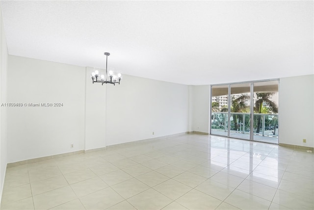 empty room with light tile patterned flooring and an inviting chandelier