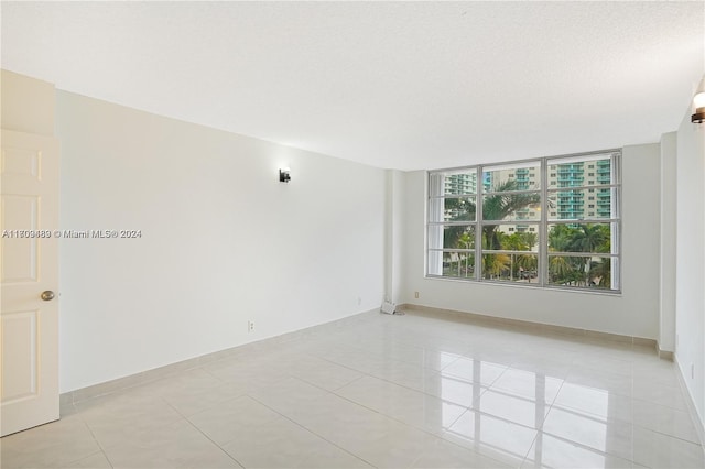 spare room featuring light tile patterned floors and a textured ceiling