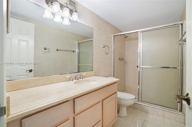 bathroom featuring vanity, tile patterned floors, toilet, tile walls, and an enclosed shower