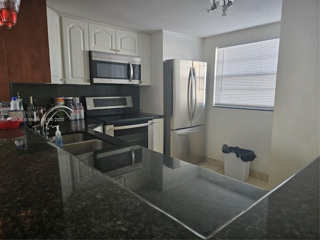 kitchen featuring sink, a textured ceiling, appliances with stainless steel finishes, decorative backsplash, and white cabinets