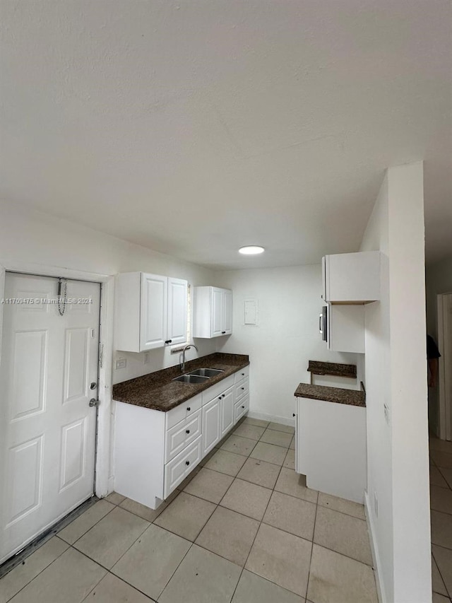 kitchen with light tile patterned flooring, white cabinetry, and sink