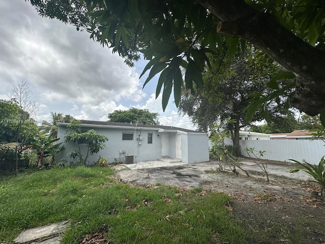 back of property featuring a lawn and central air condition unit