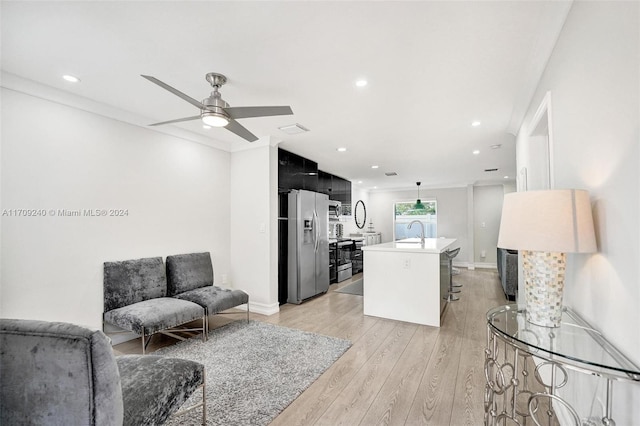 living room featuring light wood-type flooring, ceiling fan, and sink