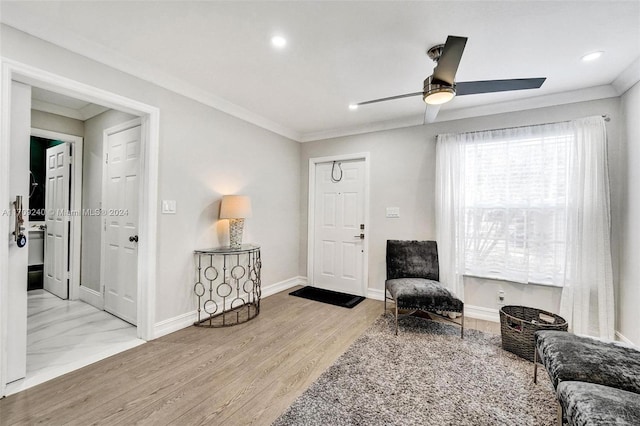 living area with crown molding, light hardwood / wood-style flooring, and ceiling fan