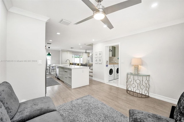 living room featuring ceiling fan, sink, crown molding, light hardwood / wood-style floors, and washer and clothes dryer