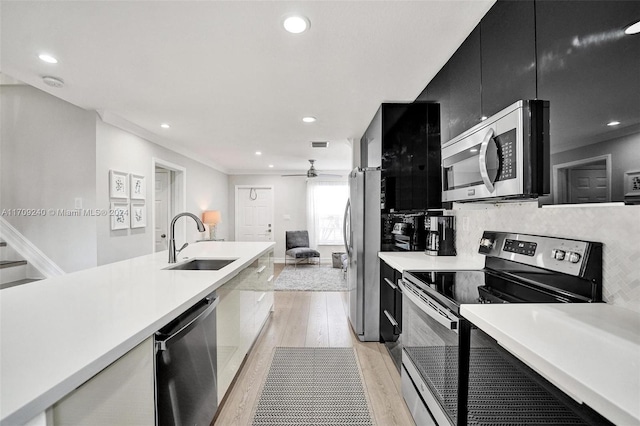 kitchen featuring tasteful backsplash, sink, appliances with stainless steel finishes, and light hardwood / wood-style flooring