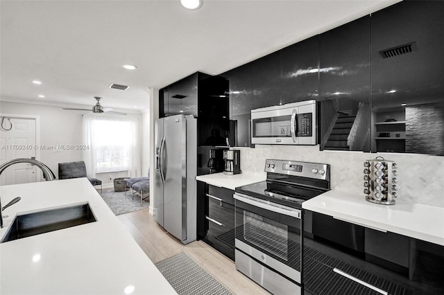 kitchen with ceiling fan, sink, stainless steel appliances, backsplash, and light hardwood / wood-style floors