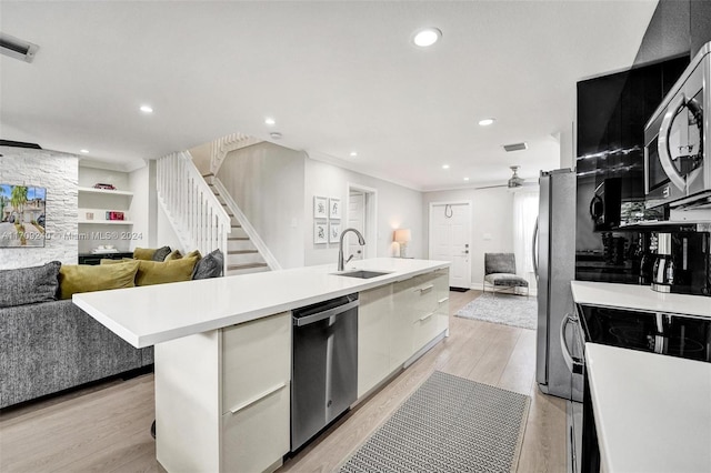 kitchen featuring appliances with stainless steel finishes, ceiling fan, a kitchen island with sink, sink, and light hardwood / wood-style floors