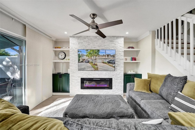 living room with a stone fireplace, built in features, light wood-type flooring, and ornamental molding