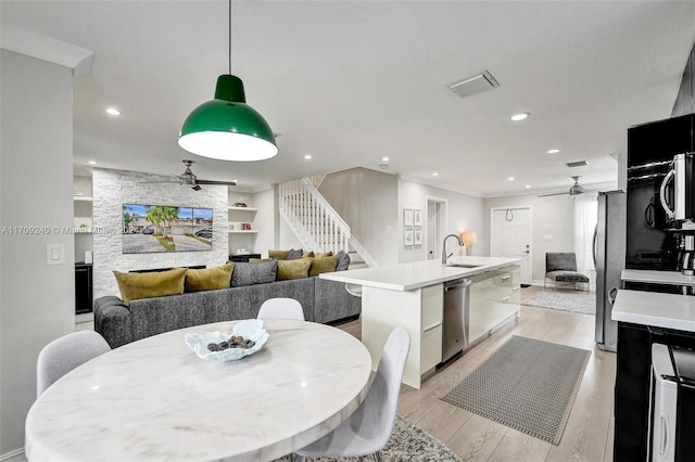 dining area with ceiling fan, sink, and light hardwood / wood-style flooring