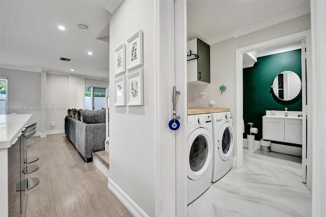 washroom with sink, washer and clothes dryer, cabinets, and light wood-type flooring