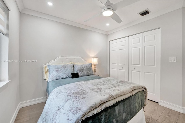 bedroom with ceiling fan, a closet, ornamental molding, and light wood-type flooring