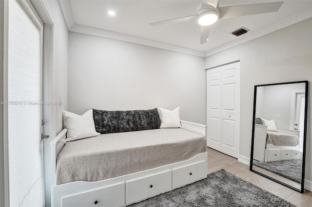 bedroom with light wood-type flooring, a closet, ceiling fan, and ornamental molding