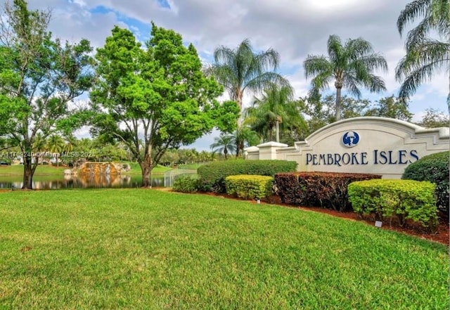 community / neighborhood sign featuring a lawn and a water view