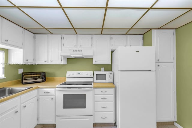 kitchen with a drop ceiling, white appliances, sink, white cabinets, and range hood