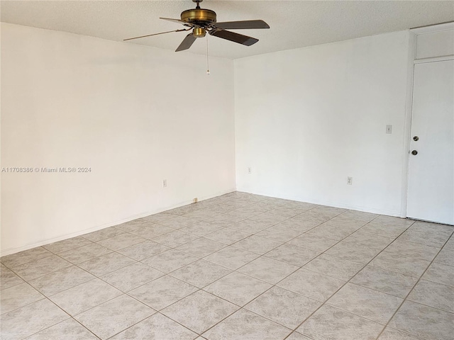 unfurnished room with ceiling fan, light tile patterned floors, and a textured ceiling