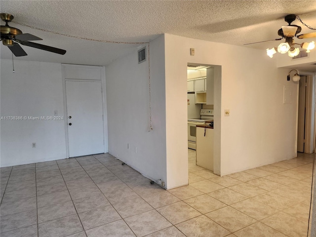 empty room featuring ceiling fan, light tile patterned floors, and a textured ceiling