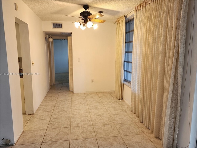 corridor with light tile patterned floors and a textured ceiling