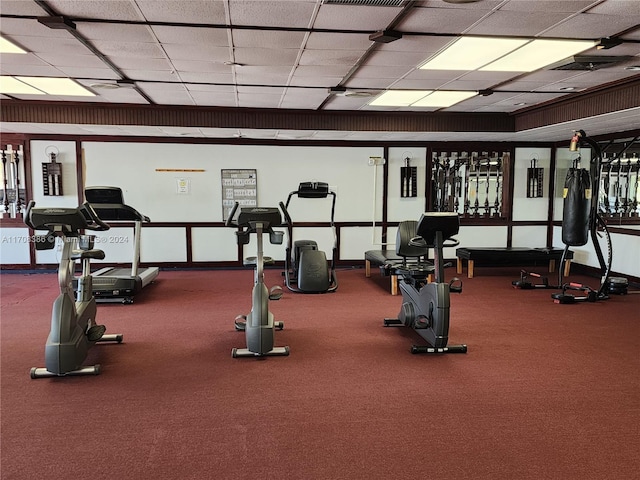 workout area featuring carpet flooring and a paneled ceiling