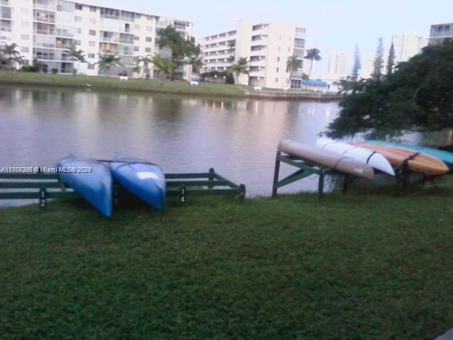 view of dock with a yard and a water view