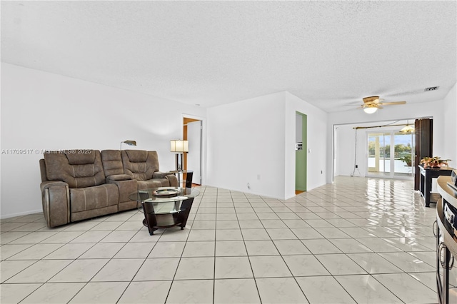 living room with ceiling fan, light tile patterned floors, and a textured ceiling