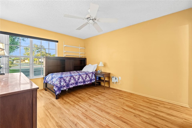 bedroom featuring ceiling fan, light hardwood / wood-style floors, and a textured ceiling