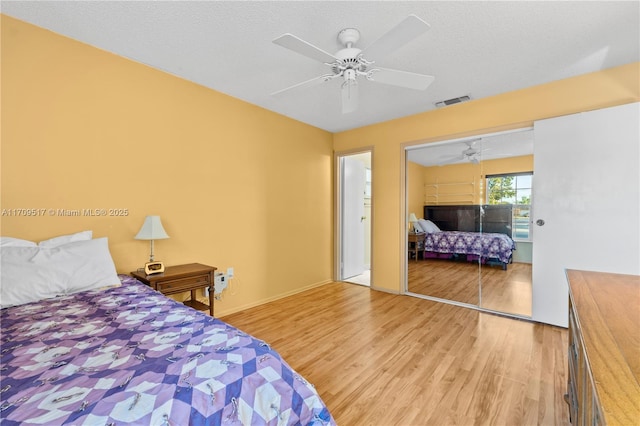 bedroom with a textured ceiling, light hardwood / wood-style flooring, a closet, and ceiling fan