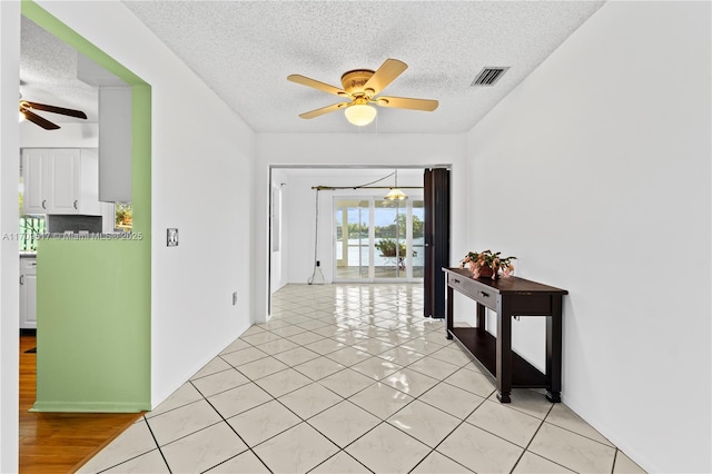 hallway with light tile patterned floors and a textured ceiling