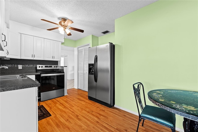 kitchen featuring ceiling fan, sink, stainless steel appliances, white cabinets, and light wood-type flooring