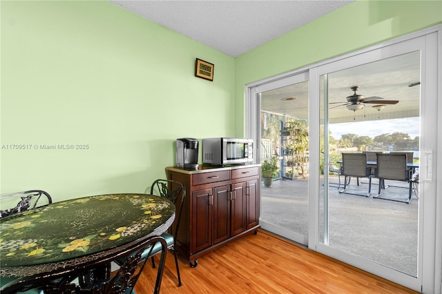 dining area with ceiling fan, a textured ceiling, and light wood-type flooring