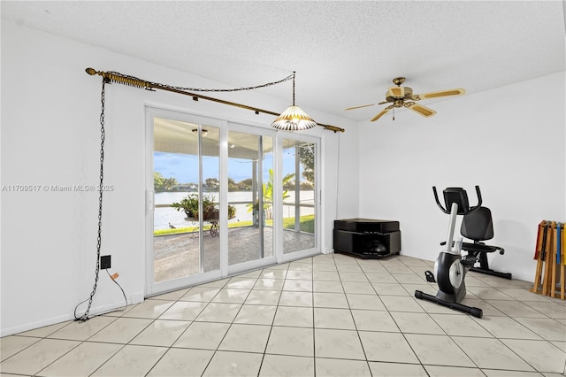 workout room with ceiling fan, light tile patterned flooring, and a textured ceiling