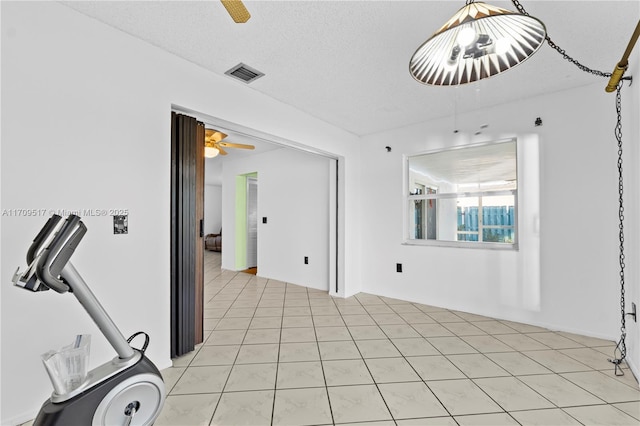 tiled spare room featuring a textured ceiling and ceiling fan