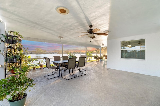 patio terrace at dusk with ceiling fan and a water view