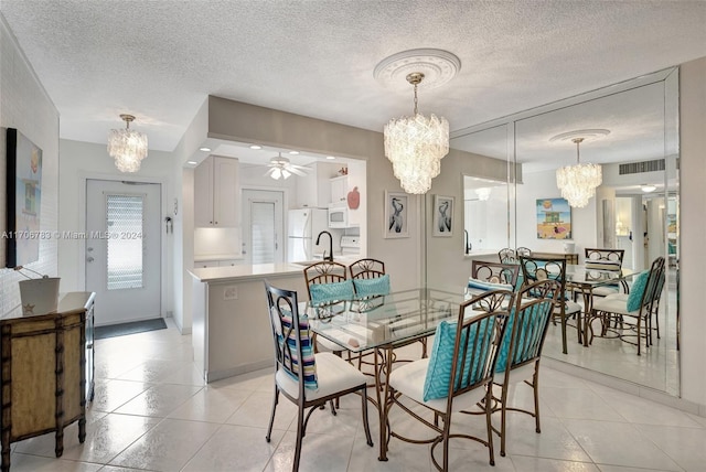 tiled dining space with ceiling fan with notable chandelier, sink, and a textured ceiling