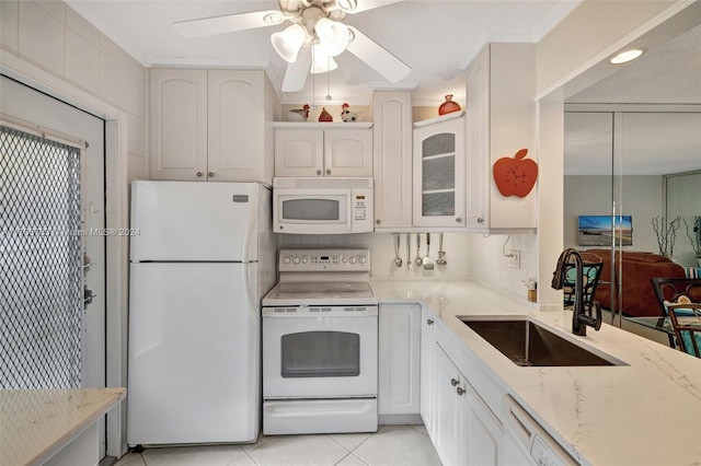 kitchen with decorative backsplash, white appliances, sink, light tile patterned floors, and white cabinetry