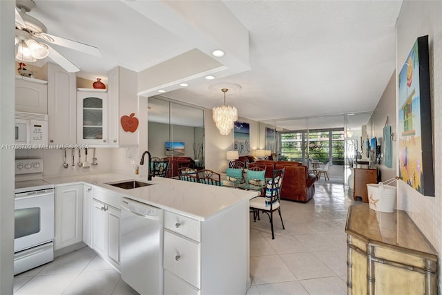 kitchen featuring white appliances, ceiling fan with notable chandelier, sink, kitchen peninsula, and white cabinetry