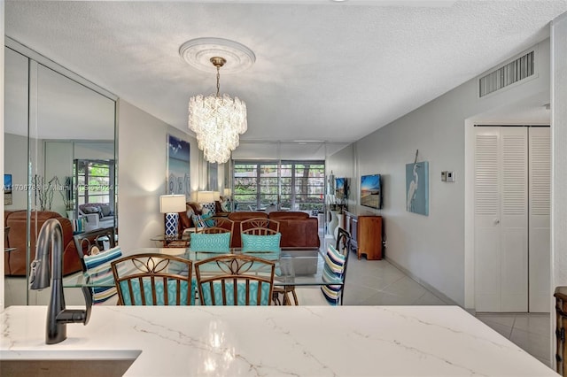 tiled dining area with sink, a textured ceiling, a healthy amount of sunlight, and a notable chandelier