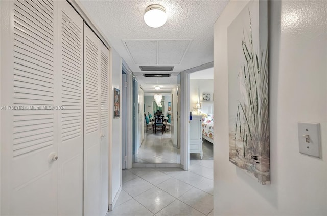 corridor with light tile patterned flooring and a textured ceiling