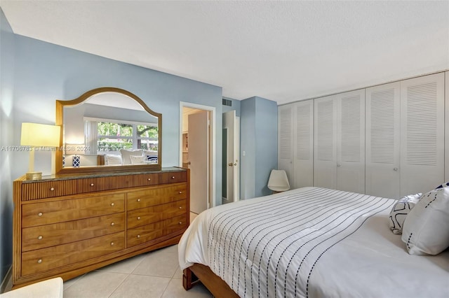 bedroom featuring light tile patterned floors, a textured ceiling, and a closet