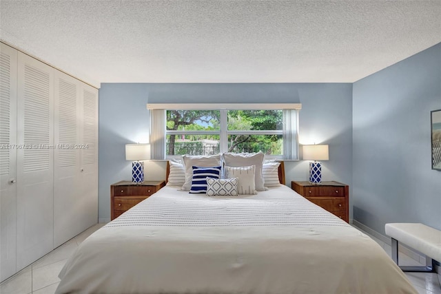 bedroom featuring light tile patterned floors, a textured ceiling, and a closet