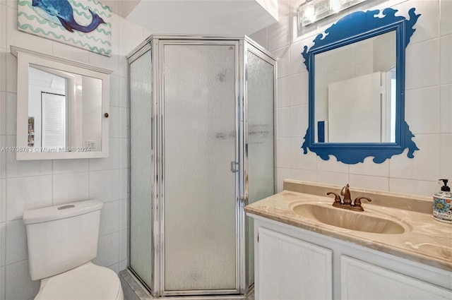 bathroom with vanity, a shower with shower door, tile walls, and toilet