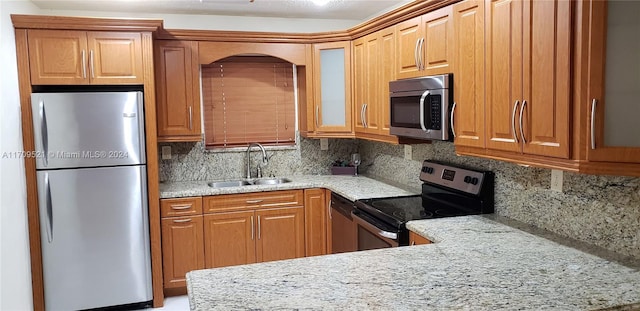 kitchen featuring decorative backsplash, light stone countertops, sink, and appliances with stainless steel finishes