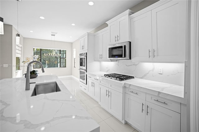 kitchen with sink, light stone countertops, decorative light fixtures, white cabinetry, and stainless steel appliances