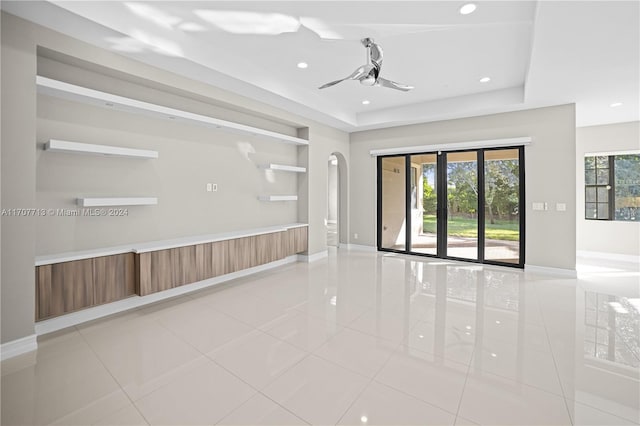 tiled empty room with a raised ceiling and ceiling fan