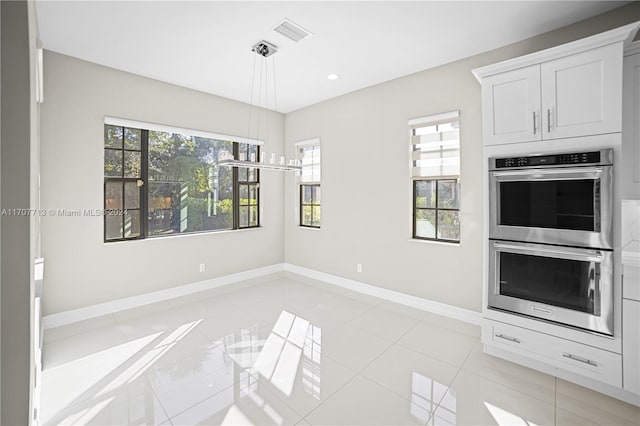 kitchen with double oven, white cabinetry, light tile patterned floors, and decorative light fixtures